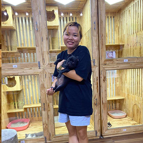 Khách hàng bế chó Pug con màu đen tại khu chuồng gỗ, ảnh bàn giao thực tế ở Chạm Pets