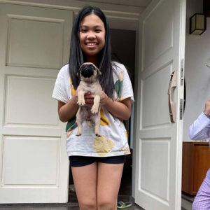 Bé gái bế chó Pug con trước cửa nhà
