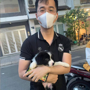 Khách hàng nam bế bé Border Collie đen trắng khi nhận bé ngoài trời