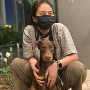 Khách hàng ngồi cạnh bé chó Doberman nâu đỏ trong ngày bàn giao tại Chạm Pets