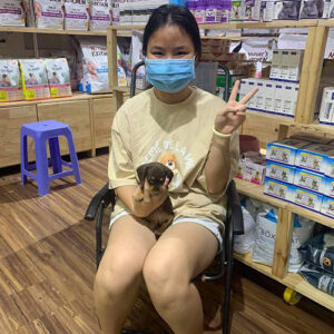 Khách nữ nhận bé chó Lạp Xưởng đen vàng tại cửa hàng Chạm Pets Family